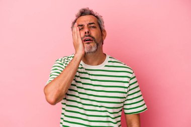 Pembe arka planda soyutlanmış orta yaşlı beyaz bir adam yorgun ve uykulu..