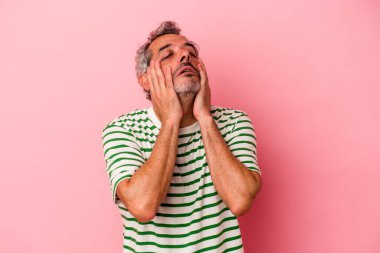 Orta yaşlı beyaz bir adam pembe arka planda izole edilmiş sızlanıyor ve ağlıyordu..
