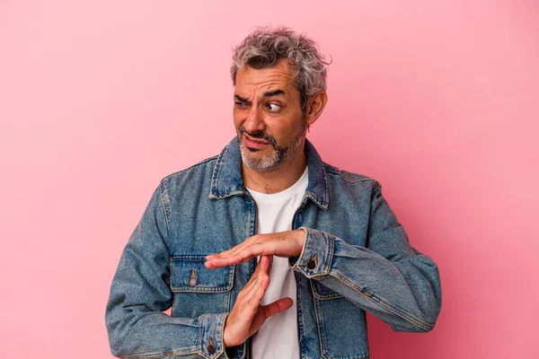 Pembe arka planda izole edilmiş orta yaşlı beyaz bir adam bir mola hareketi gösteriyor..