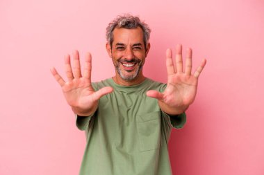 Pembe arka planda izole edilmiş orta yaşlı beyaz adam on numarayı elleriyle gösteriyor..