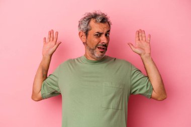 Pembe arka planda izole edilmiş orta yaşlı beyaz bir adam yakın bir tehlike nedeniyle şoka uğruyor.