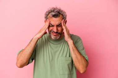 Orta yaşlı beyaz bir adam pembe arka planda izole edilmiş, başı ağrıyor, yüzüne dokunuyor..