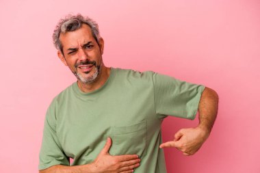 Orta yaşlı beyaz bir adam pembe arka planda izole edilmiş, karaciğer ağrısı, mide ağrısı var..