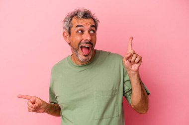 Pembe arka planda izole edilmiş orta yaşlı beyaz bir adam farklı fotokopi alanlarını gösteriyor, birini seçiyor, parmaklarıyla gösteriyor..