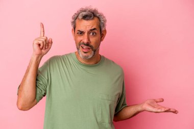 Orta yaşlı beyaz bir adam pembe arka planda izole edilmiş ve elinde bir ürün var..