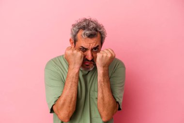 Orta yaşlı, beyaz bir adam pembe arka planda izole edilmiş. Yumruk atıyor, sinirleniyor, kavga ediyor..