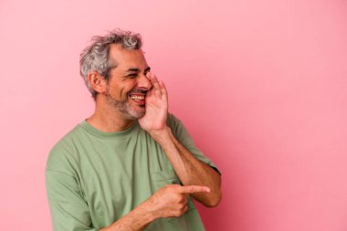 Orta yaşlı beyaz bir adam pembe arka planda izole edilmiş. Dedikodu yapıyor, bir şeyleri bildiriyor..