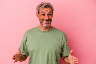 Orta yaşlı beyaz bir adam pembe arka planda izole edilmiş iki eliyle bir şey tutuyor, ürün sunumu..