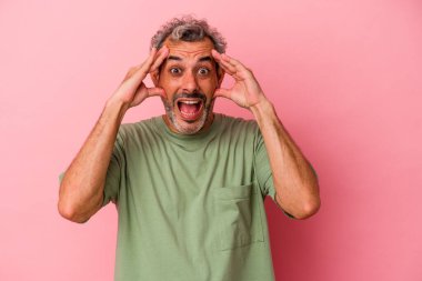 Orta yaşlı beyaz bir adam pembe arka planda izole edilmiş. Hoş bir sürpriz bekliyor. Heyecanlı ve el kaldırıyor..