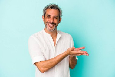 Mavi arka planda izole edilmiş orta yaşlı beyaz bir adam bir palmiye üzerinde bir kopya alanı tutuyor..