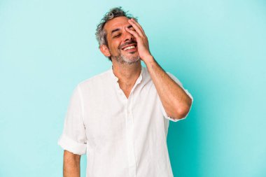 Mavi arka planda izole edilmiş orta yaşlı beyaz bir adam güler, kaygısız, doğal duygular.