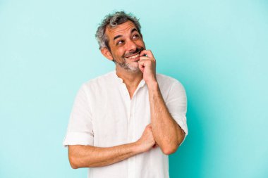 Mavi arka planda izole edilmiş orta yaşlı beyaz bir adam rahatlamış fotokopi odasına bakan bir şey düşünüyor..