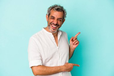 Mavi arka planda izole edilmiş orta yaşlı beyaz bir adam işaret parmağıyla fotokopi alanını işaret ederek heyecan ve arzusunu ifade ediyor..