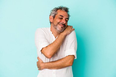 Orta yaşlı beyaz bir adam mavi arka planda izole edilmiş, güler yüzlü ve mutlu..