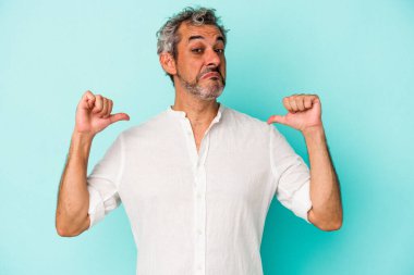 Mavi arka planda izole edilmiş orta yaşlı beyaz adam gururlu ve kendinden emin hissediyor, örnek olarak..