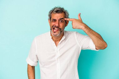 Mavi arka planda izole edilmiş orta yaşlı beyaz bir adam işaret parmağıyla hayal kırıklığı jesti yapıyor..