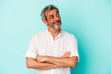 Mavi arka planda izole edilmiş orta yaşlı beyaz adam hedeflerine ve amaçlarına ulaşmayı hayal ediyor.