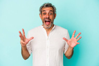 Mavi arka planda izole edilmiş orta yaşlı beyaz bir adam gökyüzüne haykırıyor, yukarı bakıyor, hayal kırıklığına uğramış..