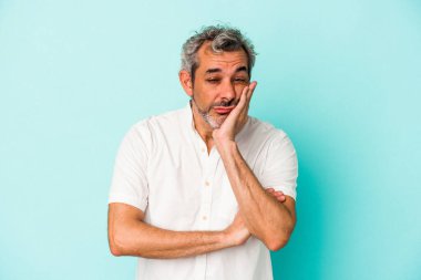 Mavi arka planda izole edilmiş orta yaşlı, yorgun ve dinlenmeye ihtiyacı olan beyaz bir adam..