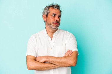 Mavi arka planda izole edilmiş orta yaşlı beyaz adam tekrarlanan bir görevden yoruldu.