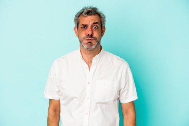 Mavi arka planda izole edilmiş orta yaşlı beyaz adamın yanakları şişer, yorgun bir ifadesi vardır. Yüz ifadesi kavramı.