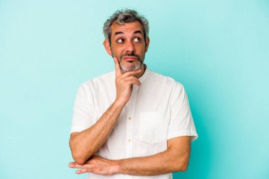 Orta yaşlı, beyaz bir adam, mavi arka planda izole edilmiş, bir strateji planlıyor, bir işin nasıl olacağını düşünüyor..