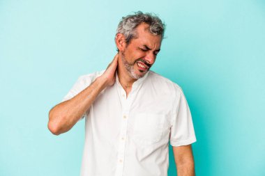 Orta yaşlı beyaz bir adam mavi arka planda izole edilmiş. Stres yüzünden boynu ağrıyor. Masaj yapıyor ve elle dokunuyor..