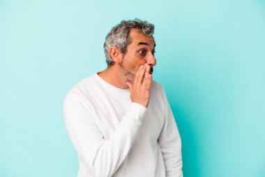 Mavi arka planda izole edilmiş orta yaşlı beyaz bir adam gördüğü bir şey yüzünden şoka uğruyor..