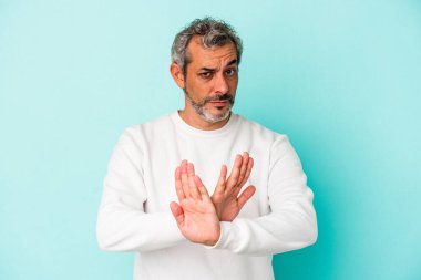 Orta yaşlı, beyaz bir adam, mavi arka planda izole edilmiş, elini uzatmış, dur işareti göstererek, seni engelliyor..