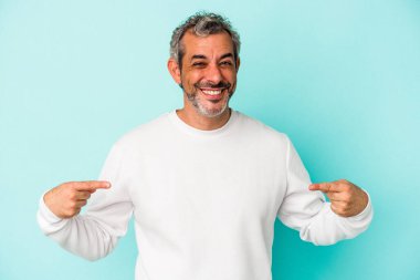 Mavi arka planda izole edilmiş orta yaşlı beyaz bir adam parmakları aşağıda, olumlu bir his var..