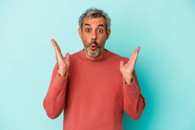 Mavi arka planda izole edilmiş orta yaşlı beyaz adam şaşırdı ve şok oldu..