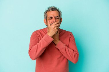 Mavi arka planda izole edilmiş orta yaşlı beyaz bir adam virüs veya enfeksiyon yüzünden boğazında ağrı hissediyor..