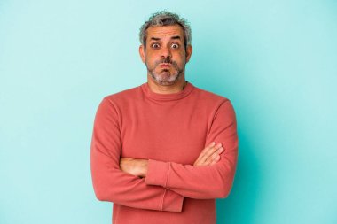 Mavi arka planda izole edilmiş orta yaşlı beyaz adamın yanakları şişer, yorgun bir ifadesi vardır. Yüz ifadesi kavramı.