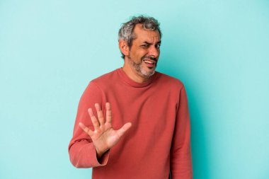 Mavi arka planda izole edilmiş orta yaşlı beyaz bir adam yakın bir tehlike nedeniyle şoka uğruyor.