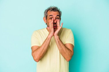 Orta yaşlı, beyaz bir adam mavi arka planda izole edilmiş. Dedikodu yapıyor, bir şeyleri bildiriyor..
