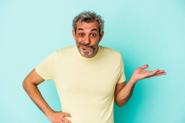 Mavi arka planda izole edilmiş orta yaşlı beyaz bir adam bir palmiye üzerinde fotokopi alanı ve belinde başka bir el tutuyor..