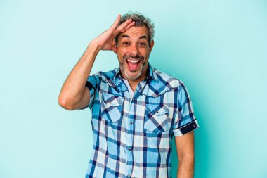 Mavi arka planda izole edilmiş orta yaşlı beyaz adam yüksek sesle bağırıyor, gözleri açık ve elleri gergin tutuyor..