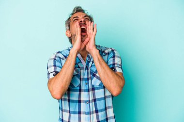Mavi arka planda izole edilmiş orta yaşlı beyaz bir adam heyecanlı bir şekilde bağırıyor..