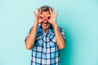Mavi arka planda izole edilmiş orta yaşlı beyaz bir adam heyecanlı..