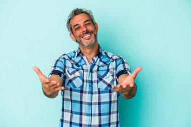 Mavi arka planda izole edilmiş orta yaşlı beyaz bir adam hoş bir ifade sergiliyor..