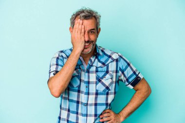 Mavi arka planda izole edilmiş orta yaşlı beyaz bir adam yüzünün yarısını palmiye ile örterek eğleniyor..