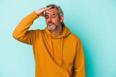 Orta yaşlı beyaz bir adam mavi arka planda izole edilmiş tapınaklara dokunuyor ve başı ağrıyor..