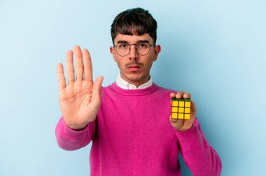 Genç melez bir ırk öğrencisi mavi arka planda izole edilmiş elini uzatmış, dur işareti göstererek seni engelliyor..