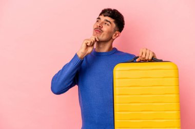 Genç melez adam pembe arka planda tek başına seyahat edecek şüpheli ve şüpheci bir ifadeyle yana bakacak..