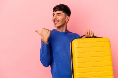 Genç melez adam pembe arka planda tek başına seyahat edecek. Baş parmak uzakta, gülerek ve kaygısızca..