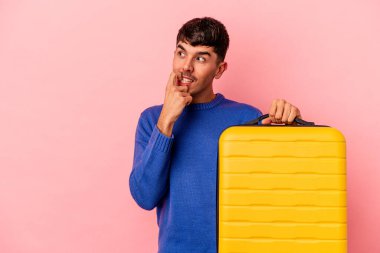 Genç melez adam pembe arka planda tek başına seyahat edecek rahat bir şekilde fotokopi odasına bakan bir şeyi düşünecek..