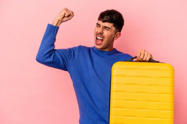 Genç melez adam pembe arka planda tek başına seyahat edecek zafer kazandıktan sonra yumruğunu kaldıracak, kazanan konsept..