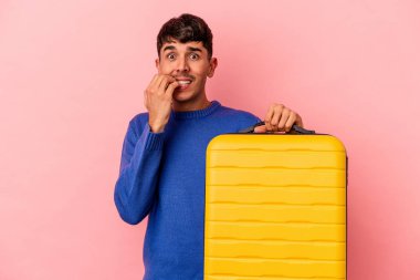 Genç melez adam pembe arka planda tek başına seyahat edecek tırnak yiyor, gergin ve çok endişeli..