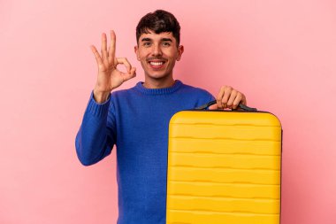 Genç melez adam pembe arka planda yalnız seyahat edecek. Neşeli ve kendinden emin..