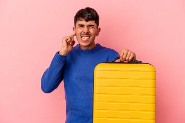 Genç melez adam seyahat edecek. Pembe arka planda tek başına. Kulakları elleriyle kapatıyor..